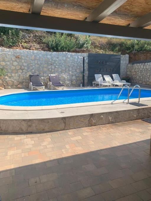 a large swimming pool with chairs and a table at Grey Beach Apartment in Stara Novalja