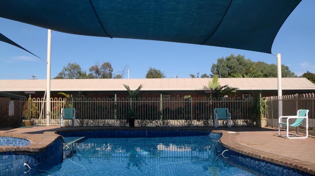 a swimming pool with two chairs and a fence at Tooleybuc Motel in Tooleybuc