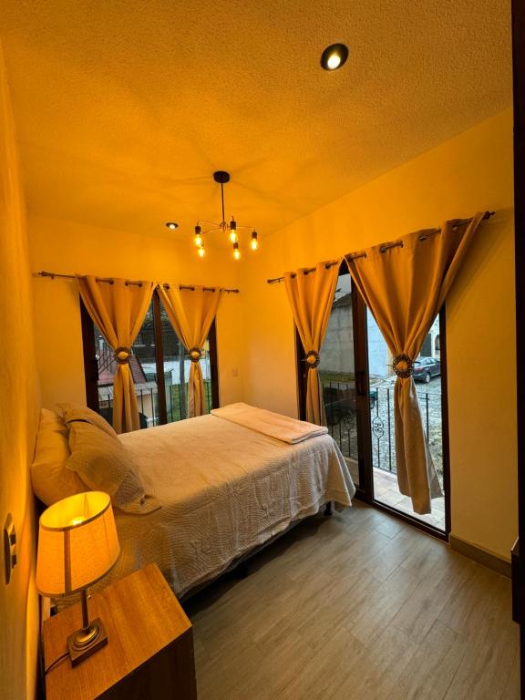 San Pedro Las HuertasにあるCasa Completa Boutique #3 cerca de Antigua Guatemalaのベッドと大きな窓のある寝室