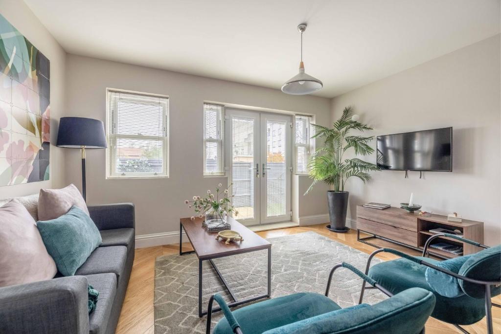 a living room with a couch and chairs and a tv at Modern 2 Bed Oasis - Private parking & Garden in Windsor