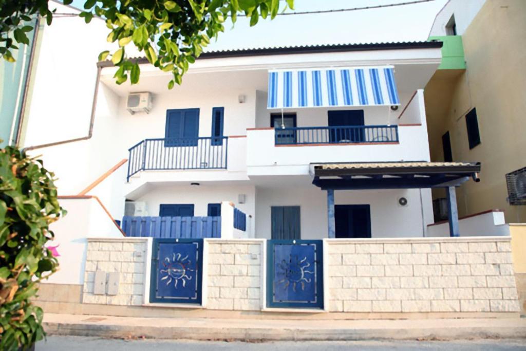 una casa blanca con puertas azules y una valla en MareinSicilia: Appartamenti del Melo, en Marina di Ragusa