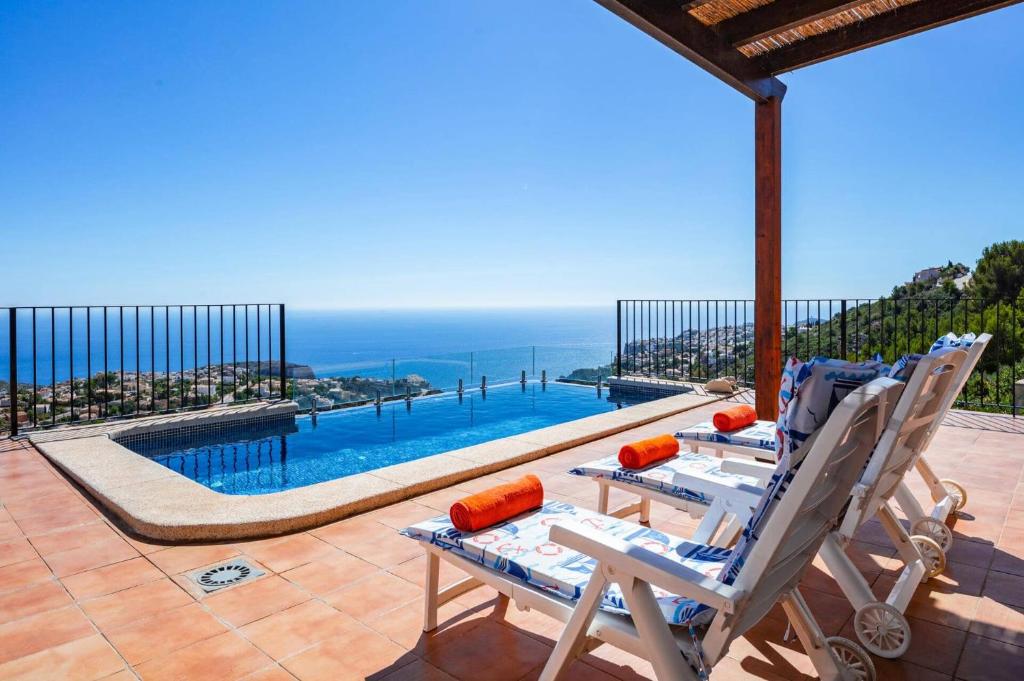 patio z 2 krzesłami i basenem w obiekcie Villa Amanecer by Villa Plus w mieście Cumbre del Sol