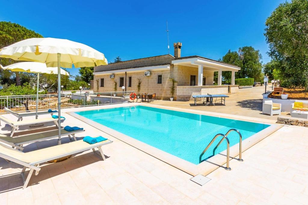 une piscine avec deux chaises et un parasol dans l'établissement Villa Guglielmo by Villa Plus, à Carovigno