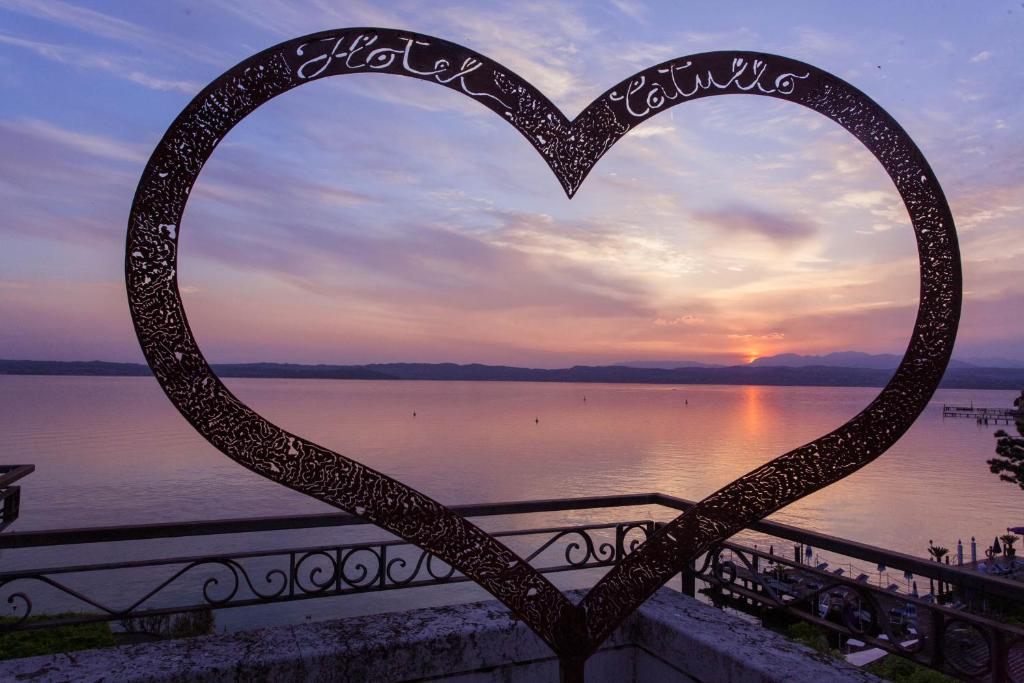 una scultura di cuore davanti a un corpo d'acqua di Hotel Catullo a Sirmione