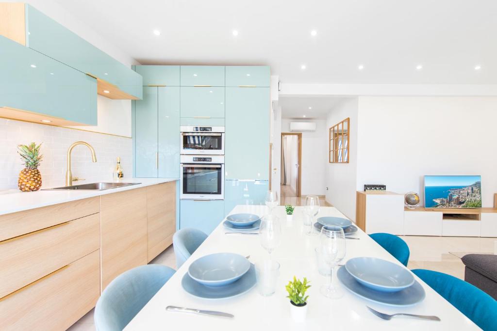 a kitchen with a white table and blue chairs at Sublime 3P à la frontière de Monaco in Beausoleil