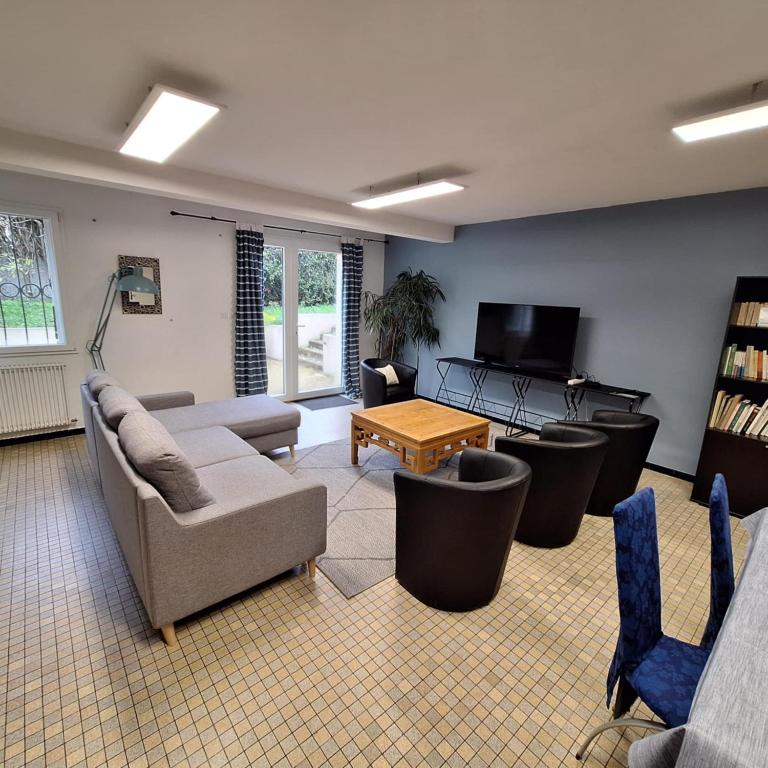 un salon avec un canapé, des chaises et une télévision dans l'établissement Appart jardin Kennedy, à Cholet