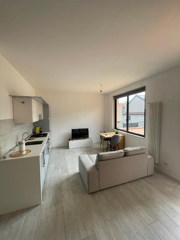 una cucina e un soggiorno con un divano e un tavolo di Appartamento nuovo vicino alla stazione a Cesano Maderno