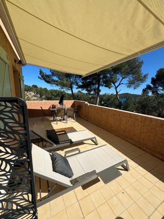 un patio avec des chaises, une table et un parasol dans l'établissement T3 Haut de gamme, vue mer au calme, à La Seyne-sur-Mer