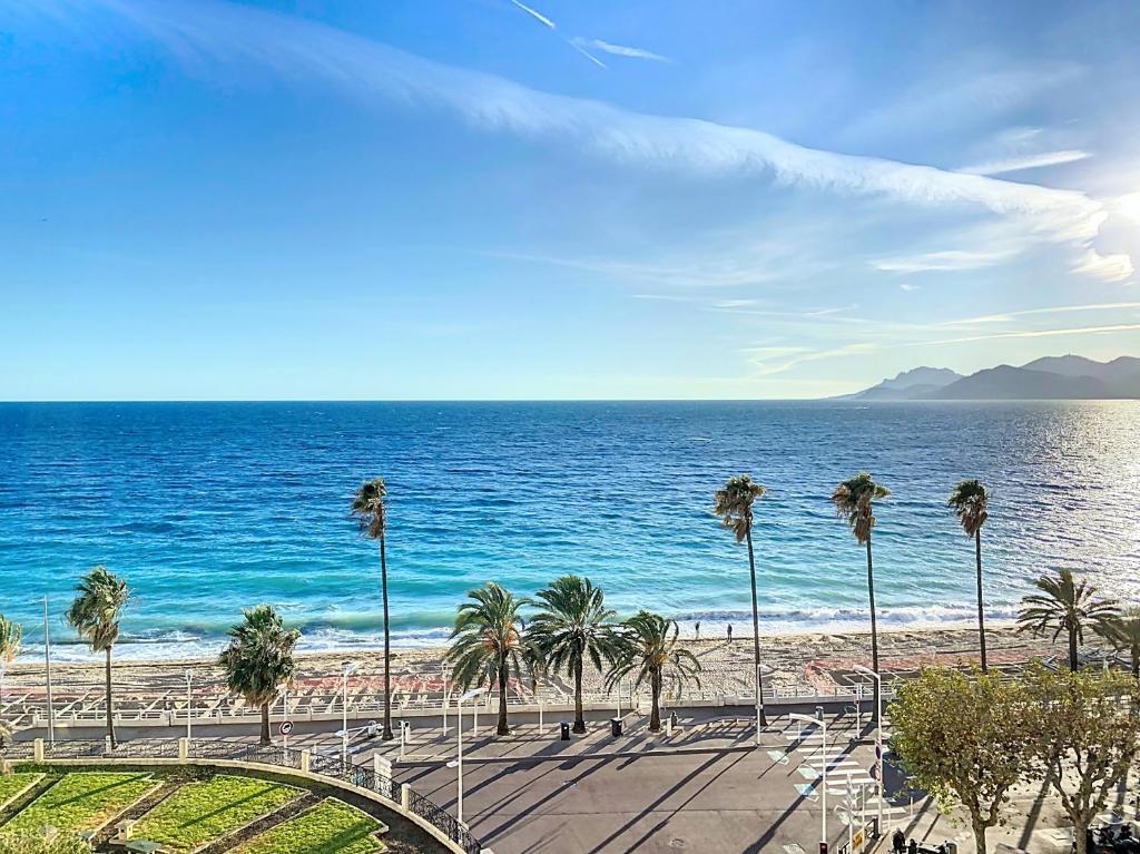 une vue sur une plage avec des palmiers et l'océan dans l'établissement Emplacement & vue exceptionnels 120L, à Cannes