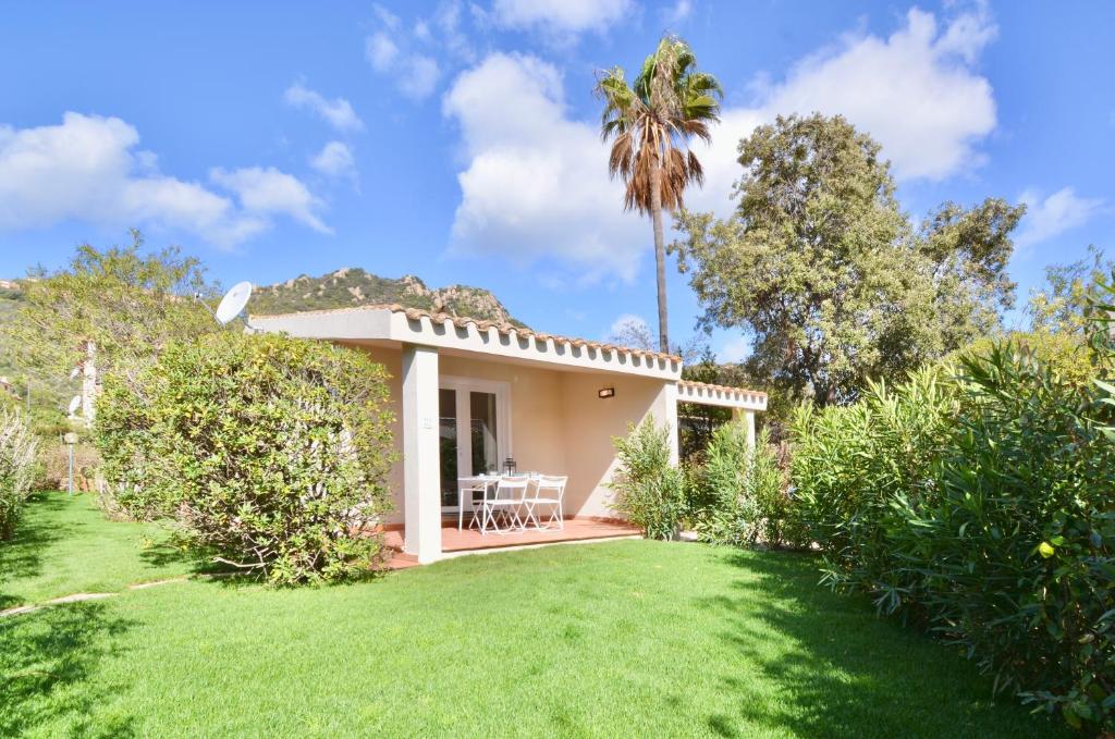 a villa with a palm tree and a yard at Residence in Costa Rei just 450 meters from the beach, apartments with air conditioning and outdoor private area in Costa Rei