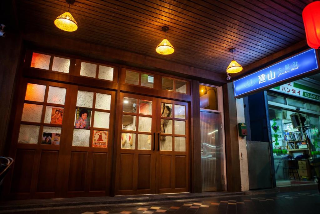 台北的住宿－建山大旅社，夜间在建筑物前面有灯的商店