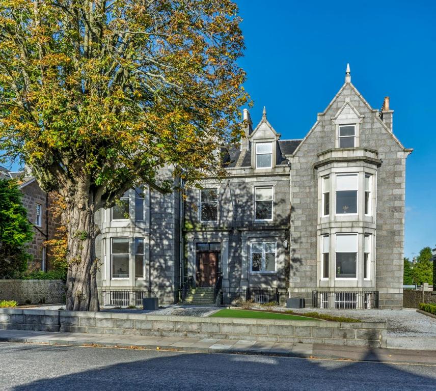 an old stone house with a tree in front of it at 8QR Rooms in Aberdeen