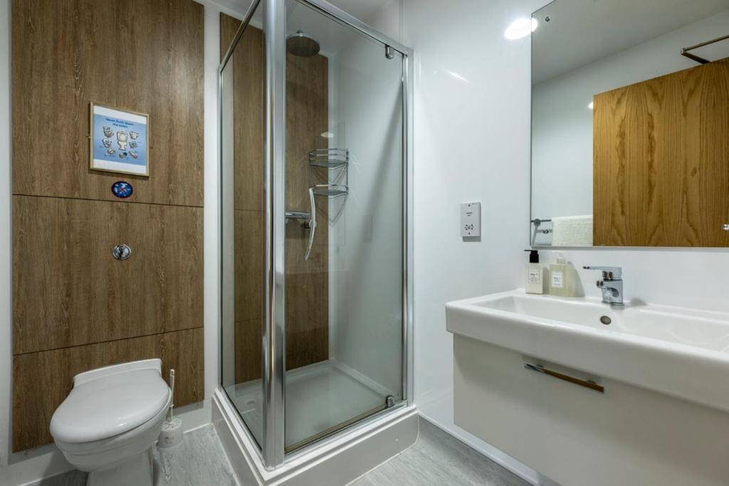 a bathroom with a shower and a toilet and a sink at 8QR Rooms in Aberdeen