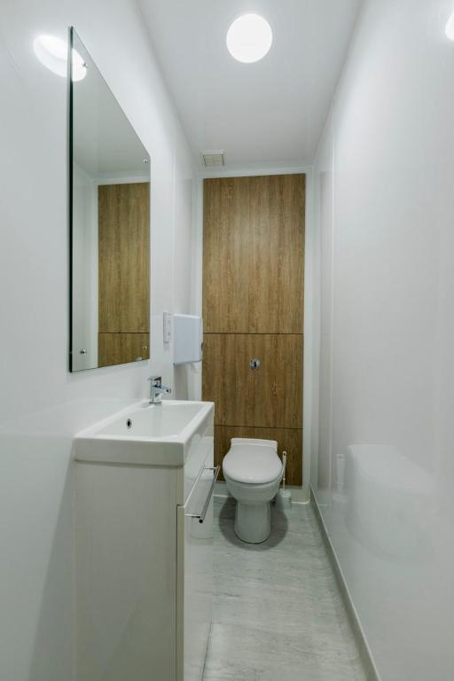 a bathroom with a toilet and a sink and a mirror at 8QR Rooms in Aberdeen
