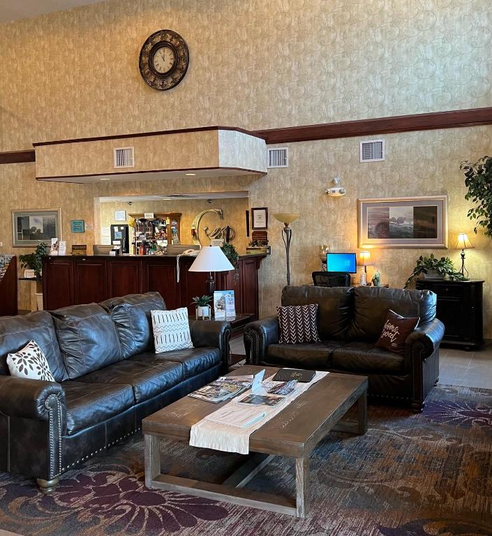 a living room with leather couches and a coffee table at GrandStay Hotel & Suites Becker in Becker