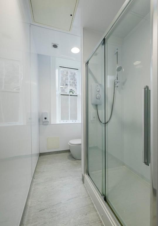 a bathroom with a glass shower and a toilet at 8QR Rooms in Aberdeen