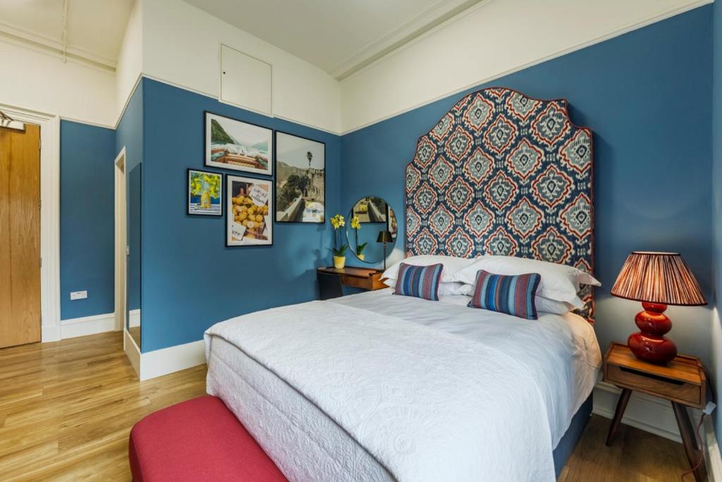 a bedroom with a large bed with a blue wall at 8QR Rooms in Aberdeen