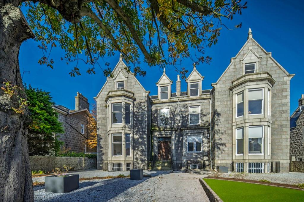 a large stone house with a tree at 8QR Rooms in Aberdeen