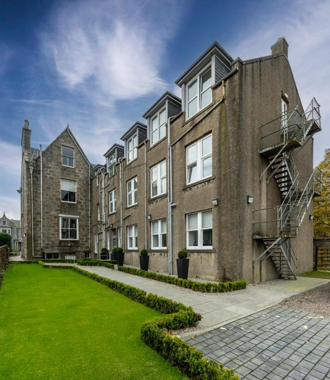 an apartment building with a green lawn in front at 8QR Rooms in Aberdeen