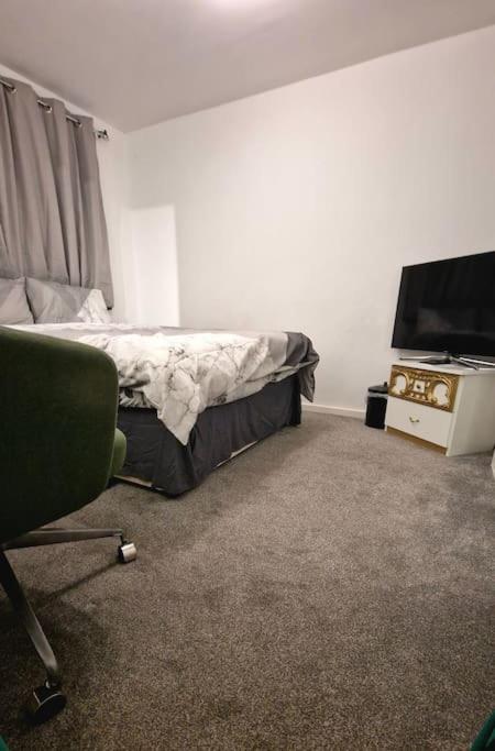a bedroom with a bed and a tv and a chair at Lizola Homes Rooms in Dagenham