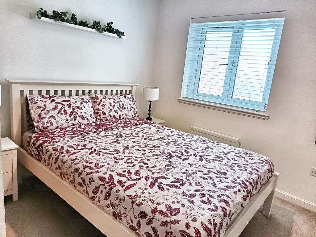 a bedroom with a bed with a red and white comforter at 4 miles to Westhill by Lains Lettings in Aberdeen