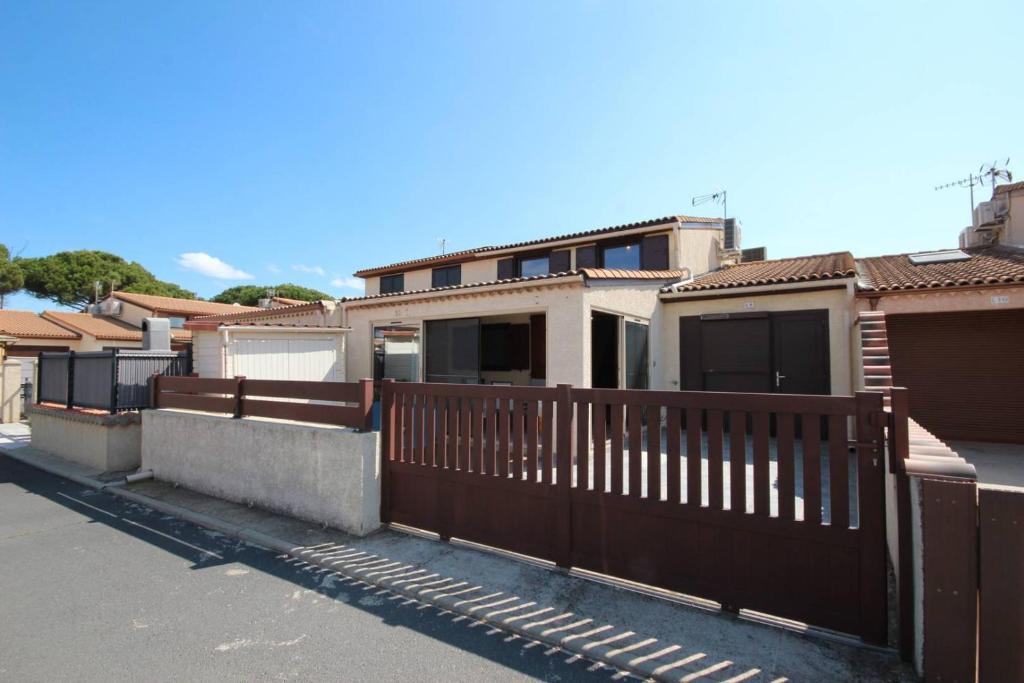 une rangée de maisons avec une clôture en bois dans l'établissement Villa climatisée, 4 couchages, 2 chambres, véranda, Résidence LES TAMARIS, accès payant pour les piscines, wifi, PORTIRAGNES PLAGE LRTAML9, à Portiragnes