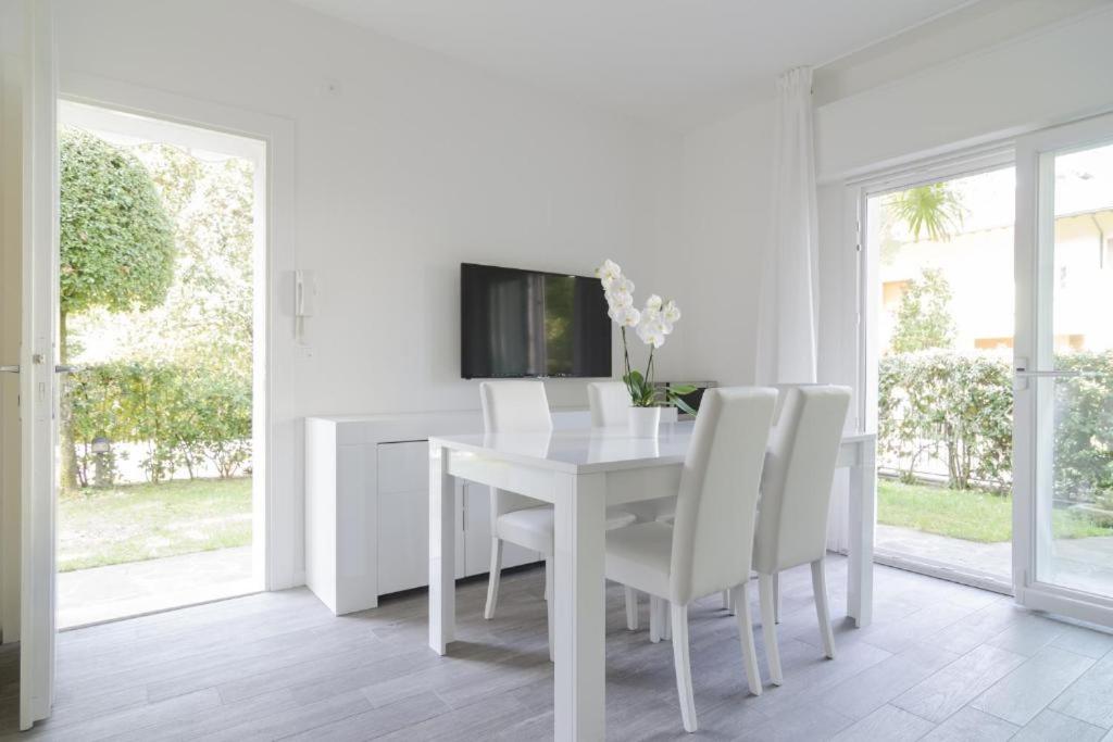 a white dining room with a white table and white chairs at Appartamenti Federica 12T in Milano Marittima