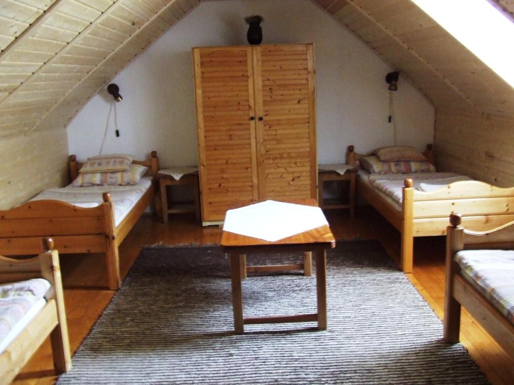 Cette chambre mansardée comprend 3 lits et une table. dans l'établissement Erdész Vendégház, à Uppony