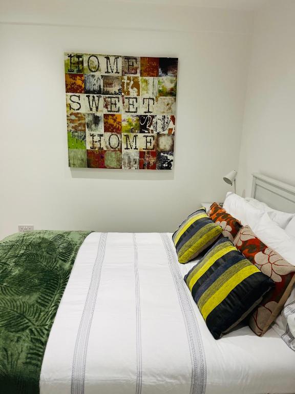 a white bed with pillows and a painting on the wall at Home Sweet Home Studio in Foleshill