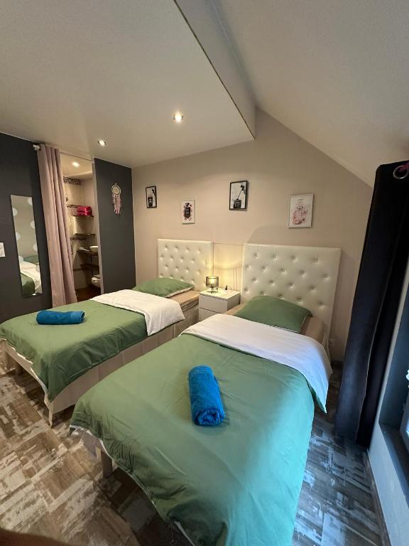 - 2 lits dans une chambre de couleur verte et blanche dans l'établissement Loc'apparts, à Beaumont-sur-Oise