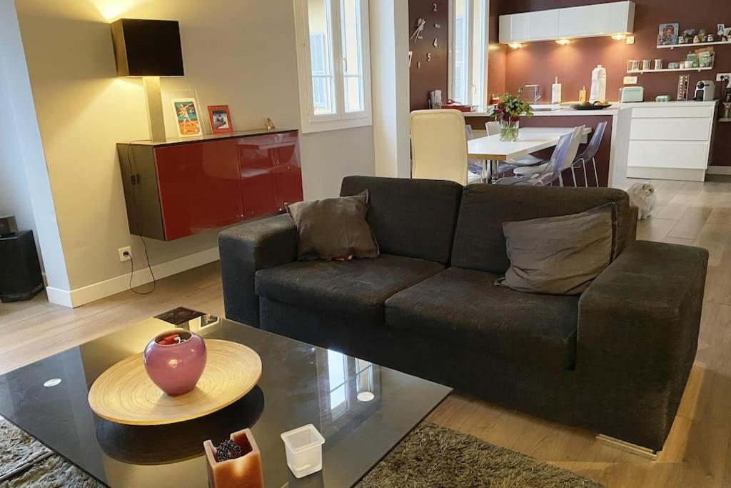 un salon avec un canapé noir et une cuisine dans l'établissement Appartement 2 chambres à 15 mn de la mer, à Nice