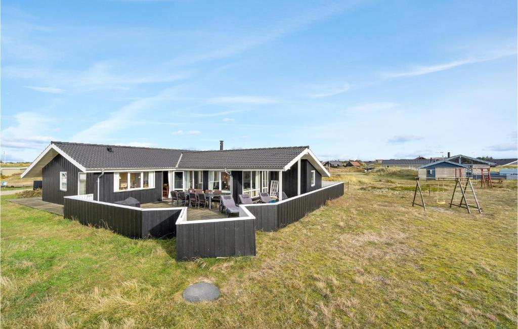 a black house on a grassy field at Holiday Home Bjerregårdsvej Hvide Sande Denm in Bjerregård