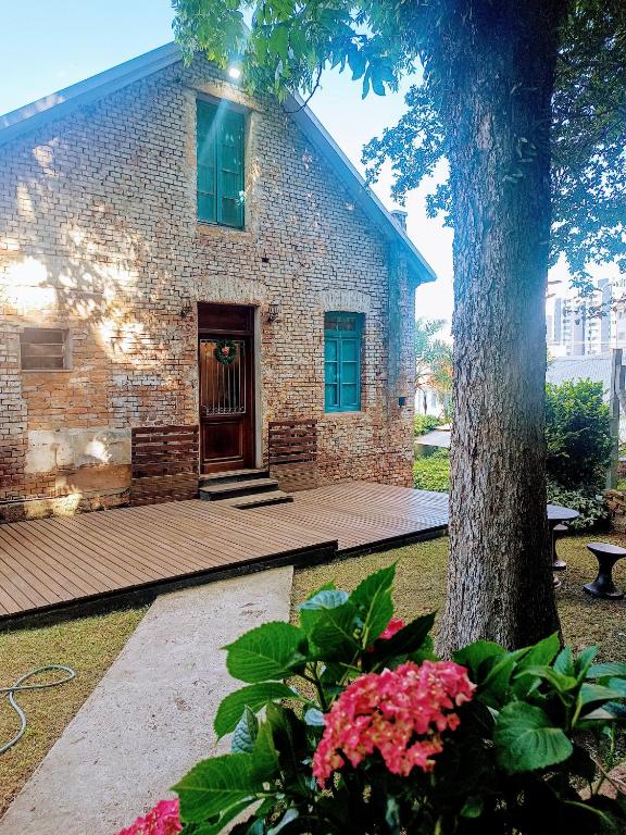 a building with a tree and flowers in front of it at Piccolo Recanto in Bento Gonçalves