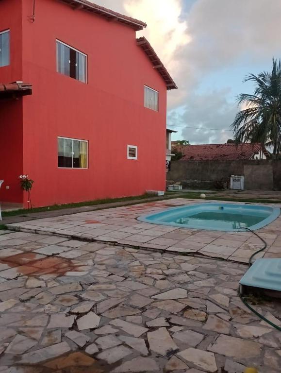 a house with a swimming pool next to a red building at casa ilha de itamaraca in Itamaracá