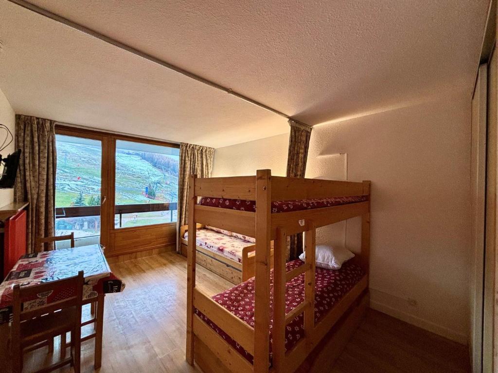 une chambre avec deux lits superposés et une table dans l'établissement Studio skis aux pieds, 4 pers, balcon sud, cœur des Menuires - FR-1-452-185, aux Menuires