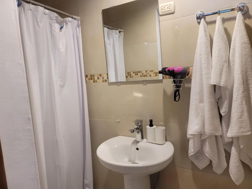 a white bathroom with a sink and a shower at small apartment in Santo Domingo