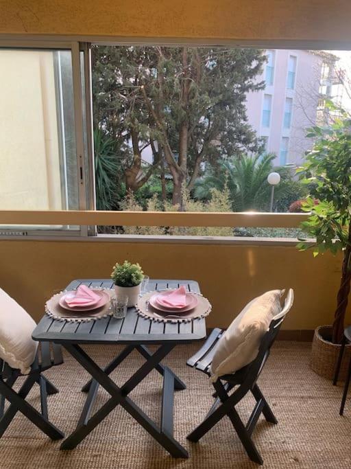 une table avec deux chaises et un oiseau assis sur un balcon dans l'établissement Appartement T2 à Sanary-sur-Mer, à Sanary-sur-Mer