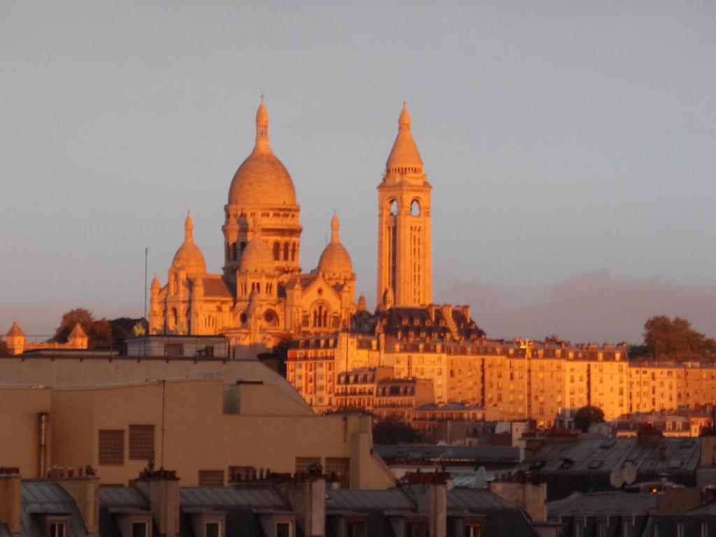 un grand bâtiment avec une tour d'horloge au sommet dans l'établissement Sweet Home Panoramique Sacré Coeur, à Paris