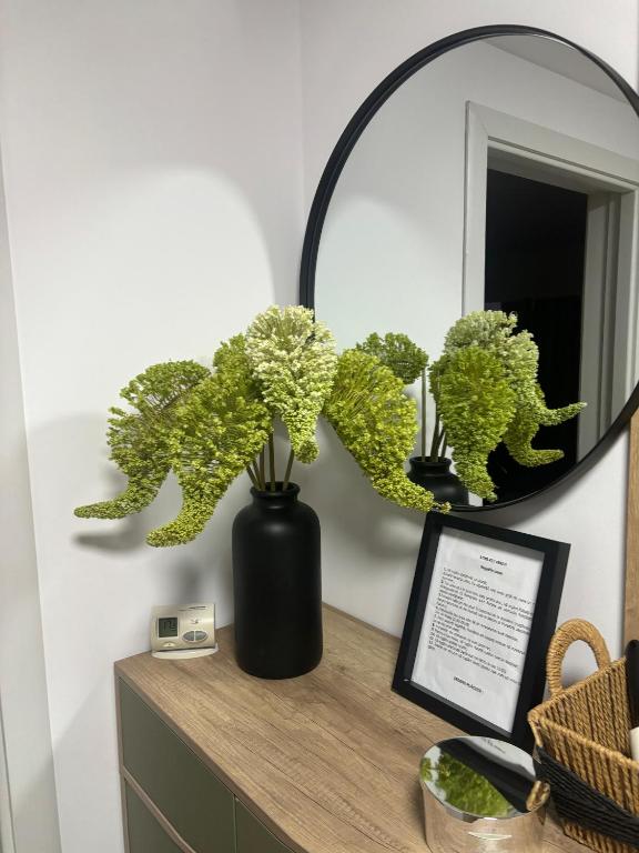 a black vase sitting on a dresser with a mirror at RORADA Apartament in Făgăraş