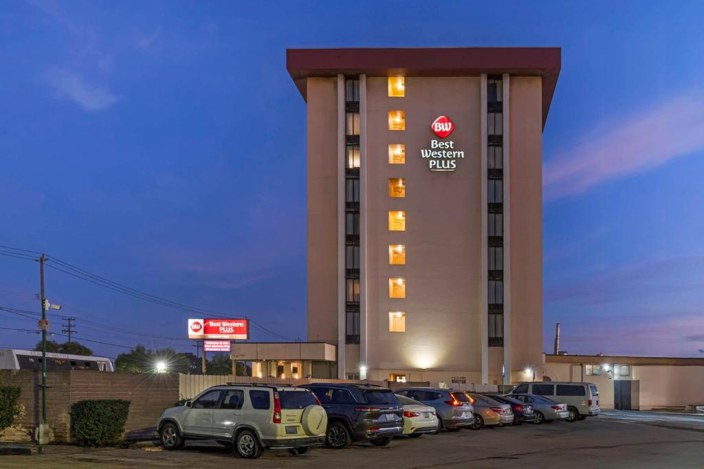 Un edificio de hotel con coches aparcados en un estacionamiento. en Best Western Plus Grosvenor Airport Hotel, en South San Francisco