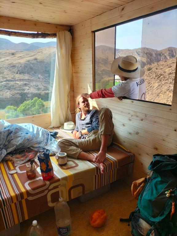 a woman sitting on a bed in a room with a window at Glamping Catarata Capua in Yura