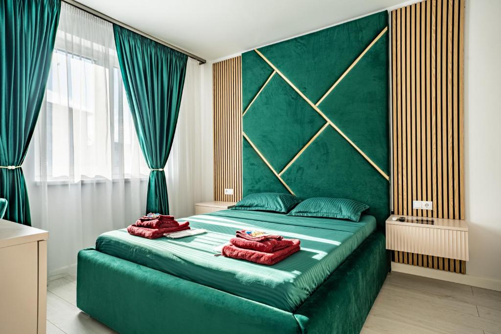 a bedroom with a green bed with red pillows on it at FLH - Robella Apartment in Sibiu