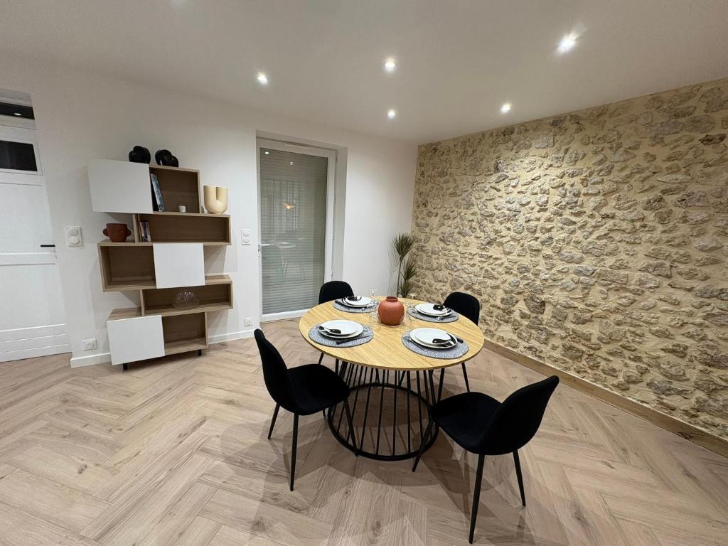 a dining room with a table and chairs and a stone wall at Chez Sof&Jé in Brie-Comte-Robert
