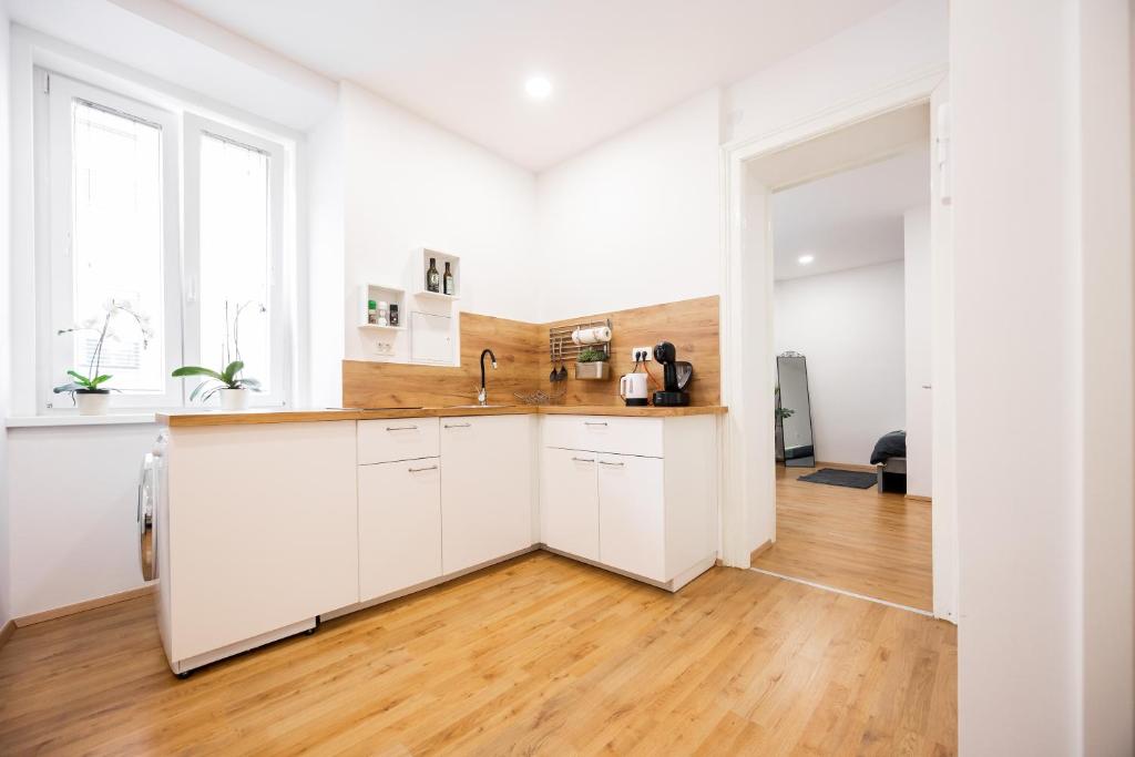 cocina con armarios blancos y suelo de madera en Appartamento Tanja Trieste, en Trieste