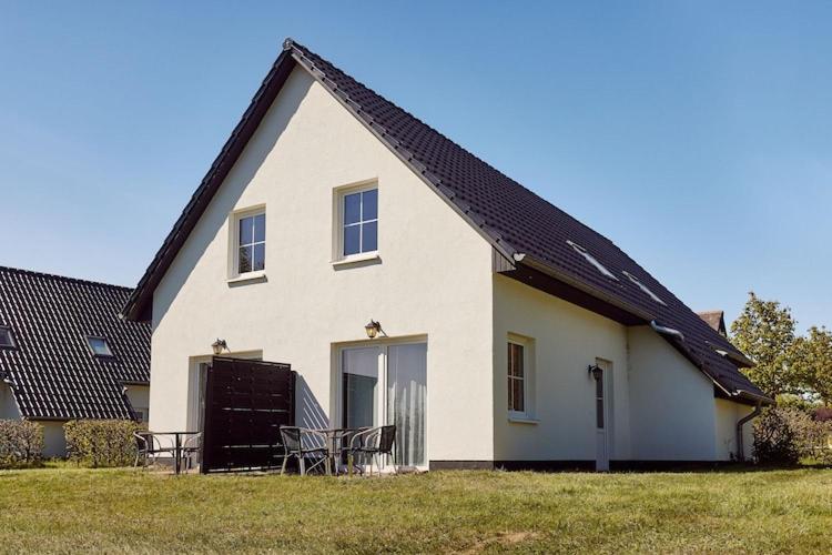 una casa bianca con una panchina davanti di Apartment im Van der Valk Resort Linstow a Dobbin-Linstow