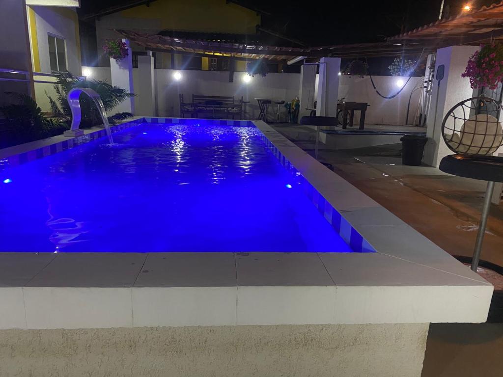 a blue swimming pool in a house at night at MAHALO 1004 Suites in Maricá