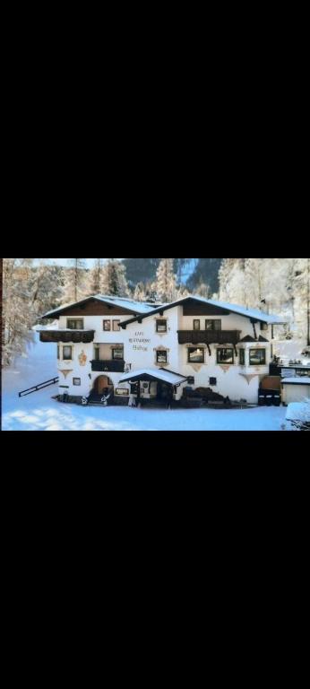 two pictures of a house in the snow at Landgasthaus Birkegg Familienzimmer in Leutasch