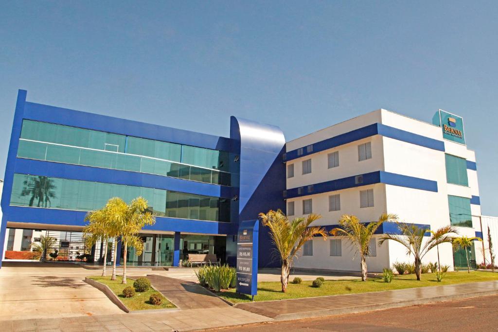 un edificio azul y blanco con palmeras delante en Bernal Hotel Econômico, en Ituiutaba