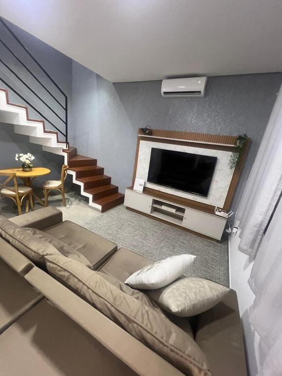a living room with a couch and a tv and stairs at Sobrado confortavel e central in Foz do Iguaçu