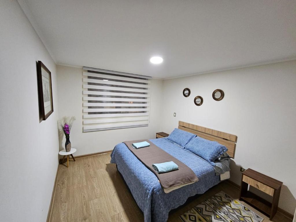 a bedroom with a blue bed and a window at Hermoso Departamento ubicado a 1 cuadra del lago Villarrica in Villarrica
